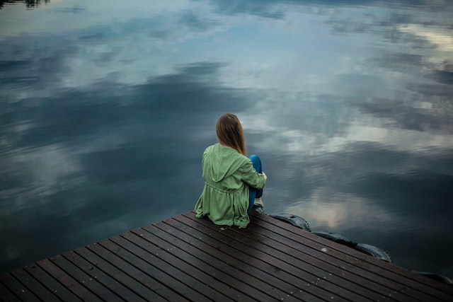 female-sitting-on-dock-looking-at-water